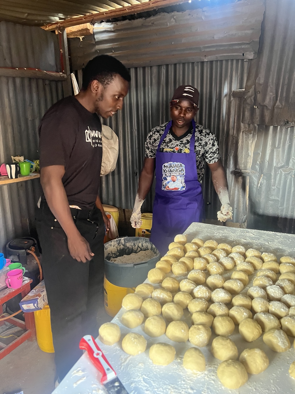 Munala listening to a local food trader as he prepares his products